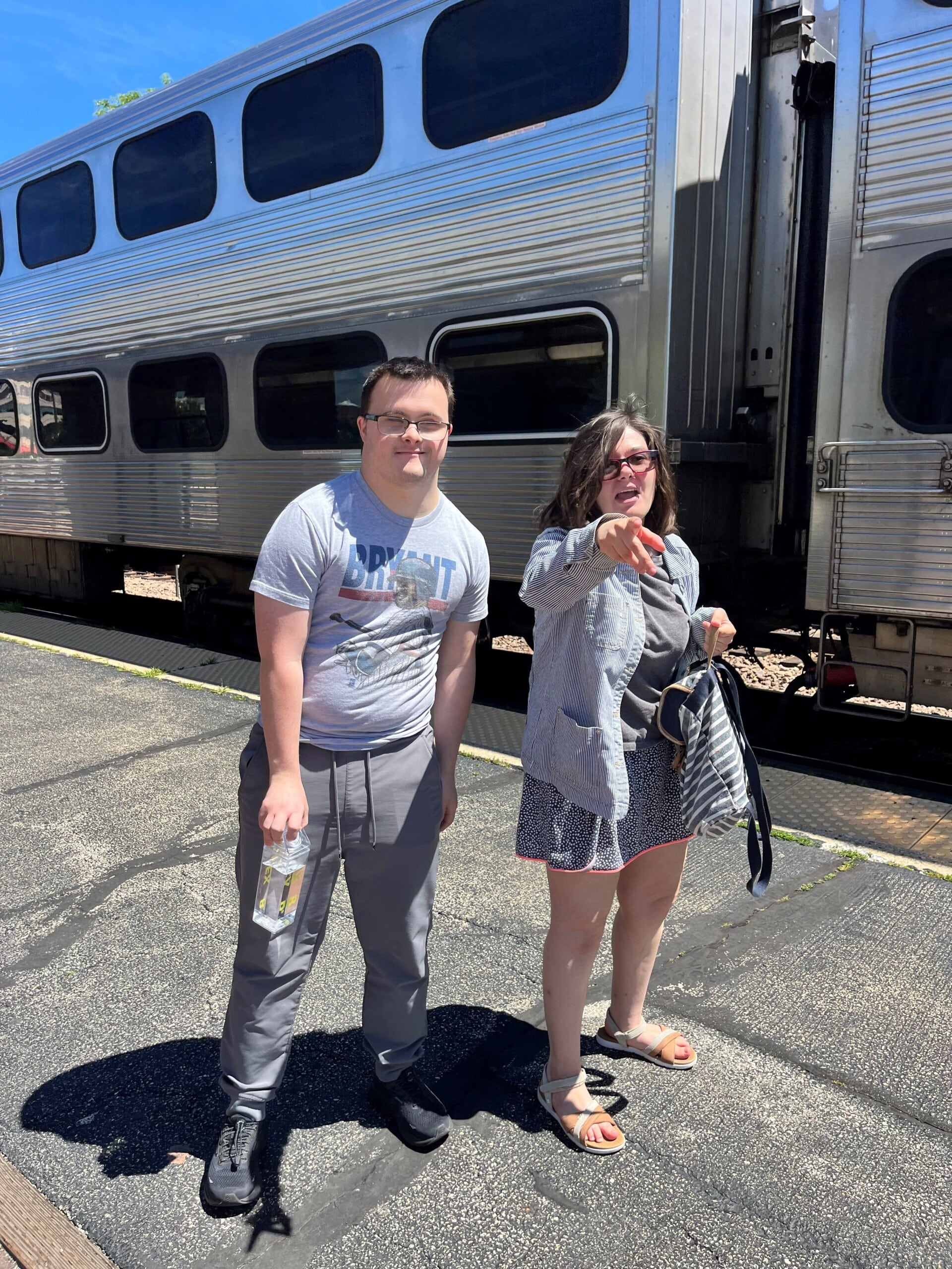 Catalyst members smiling outside a Metra train as part of their community resource session where they took the train by themselves.