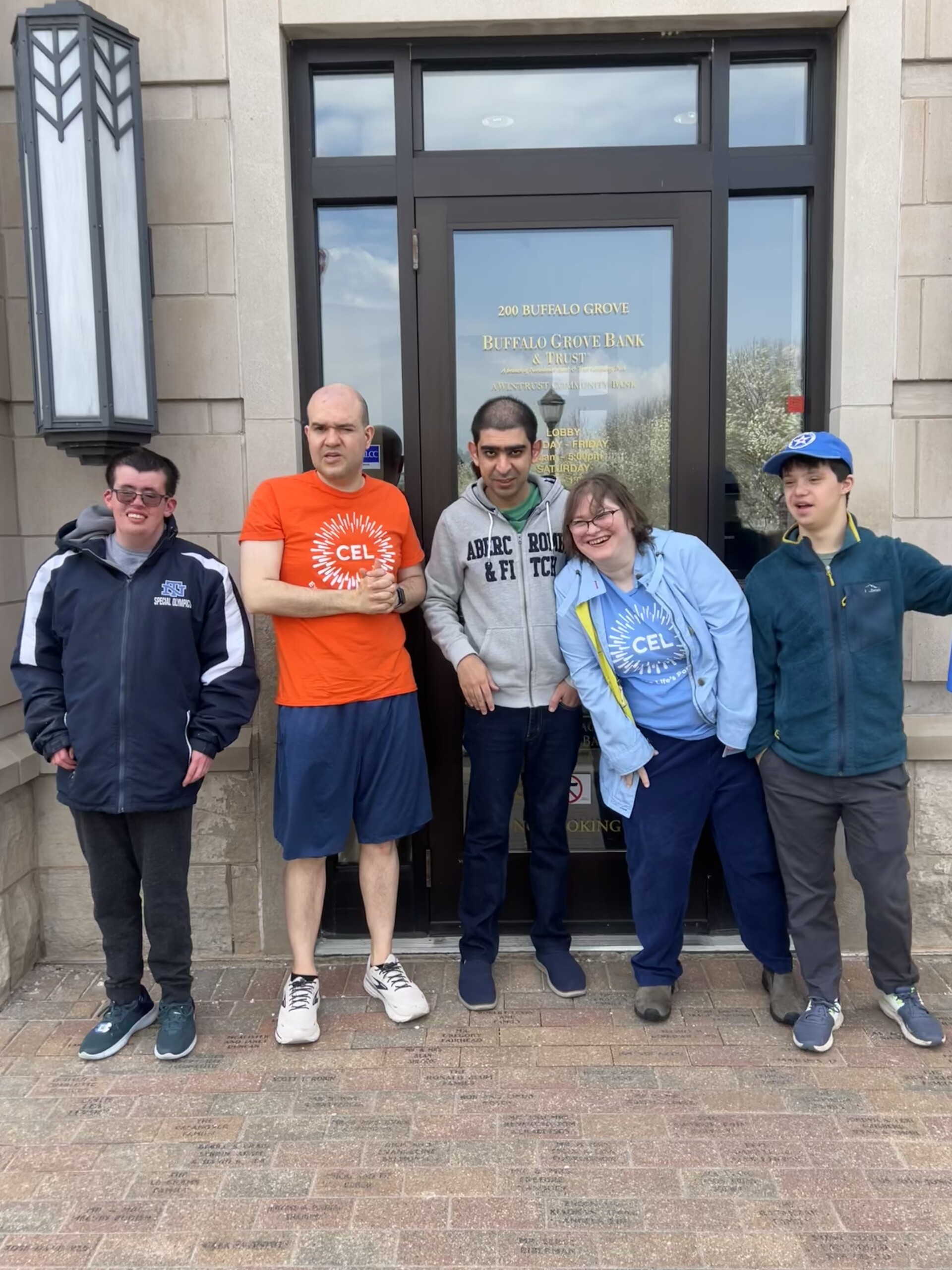 Diverse group of Catalyst life skills program members smiling outside a bank during a session focused on community resources.